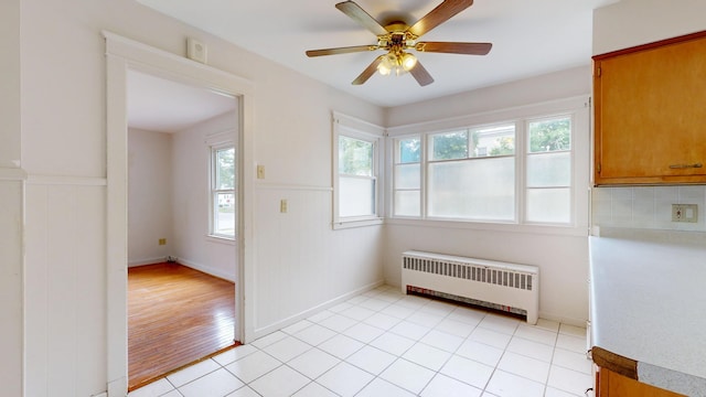 69 Androscoggin Ave, Lewiston, ME 04240 - unfurnished dining area featuring radiator heating unit, plenty of natural light, wainscoting, ceiling fan, and light wood-style floors