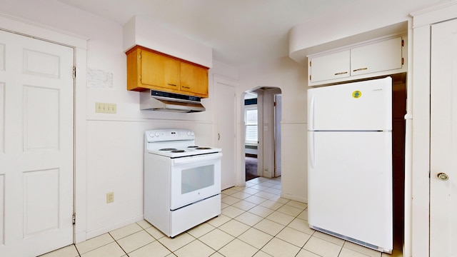 69 Androscoggin Ave, Lewiston, ME 04240 - kitchen with white appliances, under cabinet range hood, arched walkways, and light tile patterned flooring