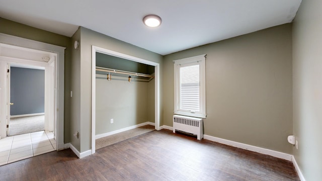 69 Androscoggin Ave, Lewiston, ME 04240 - unfurnished bedroom featuring radiator, wood finished floors, and a closet