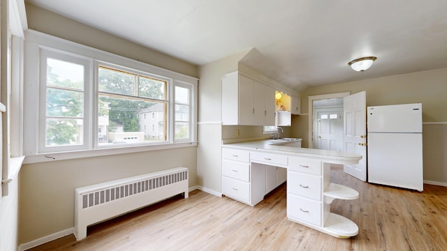 69 Androscoggin Ave, Lewiston, ME 04240 - kitchen featuring freestanding refrigerator, radiator, white cabinetry, and light wood-style floors