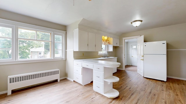 69 Androscoggin Ave, Lewiston, ME 04240 - kitchen with freestanding refrigerator, radiator, light wood finished floors, and white cabinets