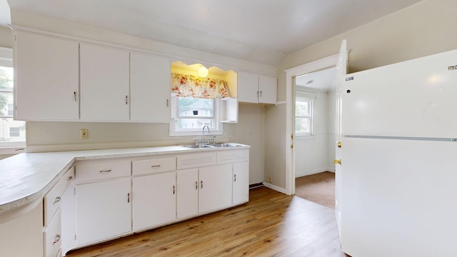 69 Androscoggin Ave, Lewiston, ME 04240 - kitchen featuring freestanding refrigerator, white cabinets, light wood-style floors, light countertops, and vaulted ceiling