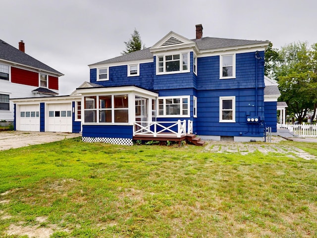 69 Androscoggin Ave, Lewiston, ME 04240 - rear view of property with a sunroom, a chimney, a deck, driveway, and a garage