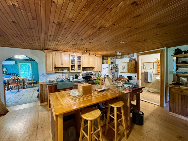 610 E Sangerville Rd, Sangerville, ME 04479 - kitchen with freestanding refrigerator, light wood-type flooring, arched walkways, glass insert cabinets, and wooden ceiling