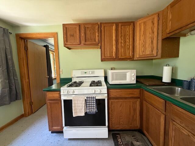 47 Tranquility Ln, Perry, ME 04667 - kitchen with white appliances, brown cabinets, dark countertops, and light flooring