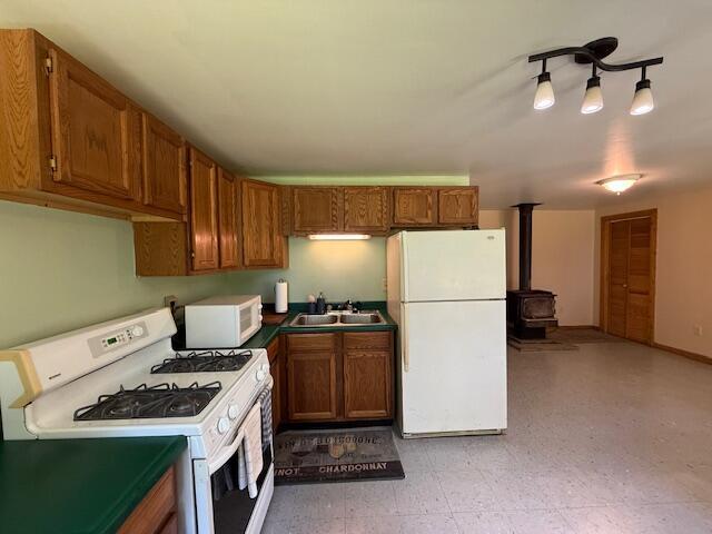47 Tranquility Ln, Perry, ME 04667 - kitchen with white appliances, a wood stove, dark countertops, and brown cabinetry
