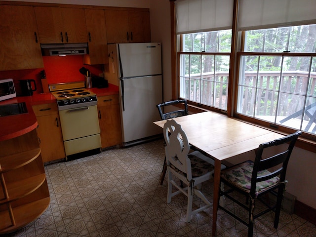 124 Main Rd, Westport Island, ME 04578 - kitchen with white appliances, range hood, light countertops, brown cabinetry, and light floors