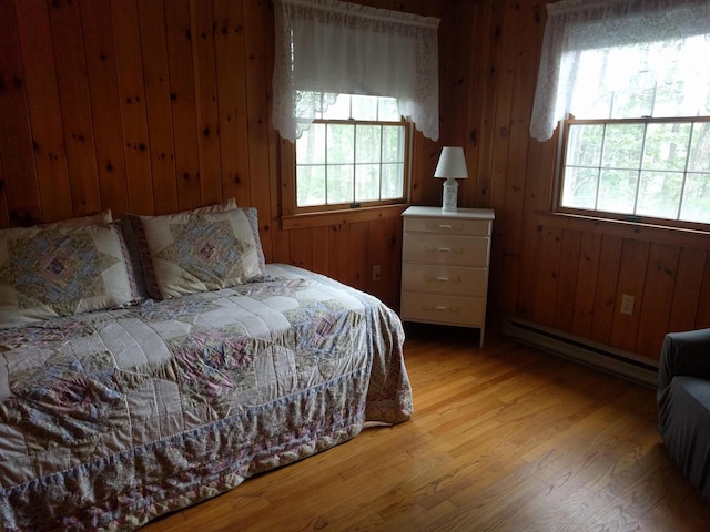 124 Main Rd, Westport Island, ME 04578 - bedroom with a baseboard radiator, multiple windows, light wood-style floors, and wood walls