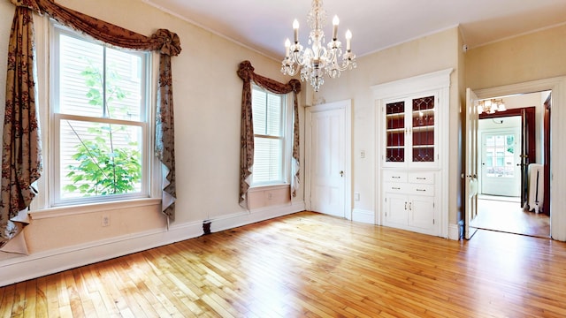 93 Fessenden St, Portland, ME 04103 - unfurnished dining area with a chandelier, light wood-style flooring, and crown molding