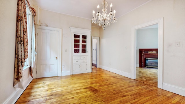 93 Fessenden St, Portland, ME 04103 - unfurnished dining area with light wood-type flooring, a chandelier, a glass covered fireplace, and ornamental molding