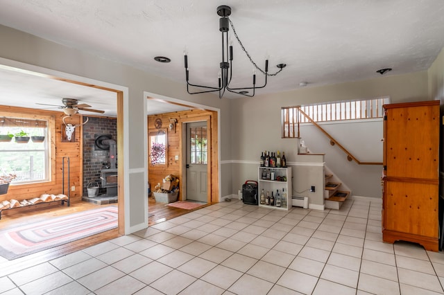 230 W Old Main Rd, Lowell, ME 04493 - living room featuring a wood stove, stairway, light tile patterned floors, a chandelier, and wood walls