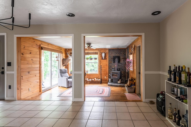 230 W Old Main Rd, Lowell, ME 04493 - foyer entrance with light tile patterned flooring, a wood stove, wood walls, and ceiling fan
