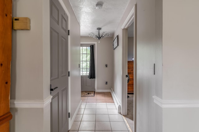 230 W Old Main Rd, Lowell, ME 04493 - hallway with light tile patterned floors, a textured ceiling, a baseboard radiator, and a chandelier