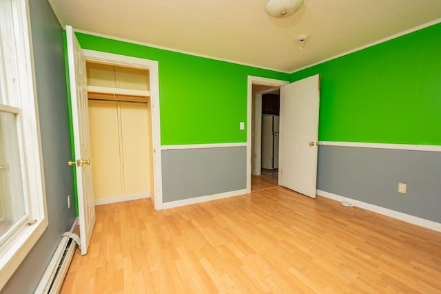 180 Lawrence St, Dover-Foxcroft, ME 04426 - unfurnished bedroom featuring baseboard heating, freestanding refrigerator, wood finished floors, a closet, and crown molding