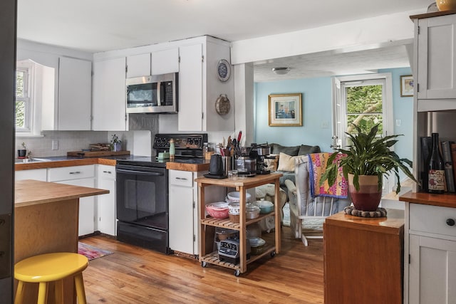 26 Wesley St Ct, Bath, ME 04530 - kitchen with stainless steel microwave, black range with electric stovetop, light wood-style flooring, and tasteful backsplash