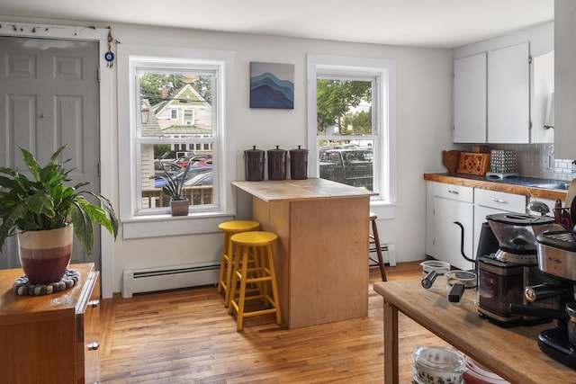26 Wesley St Ct, Bath, ME 04530 - kitchen featuring a baseboard heating unit, white cabinetry, light wood-style floors, and tasteful backsplash