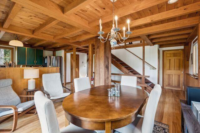 911 Orion Point Way, Harpswell, ME 04079 - dining space with a wood ceiling with exposed beams, wood finished floors, stairs, a chandelier, and wooden walls