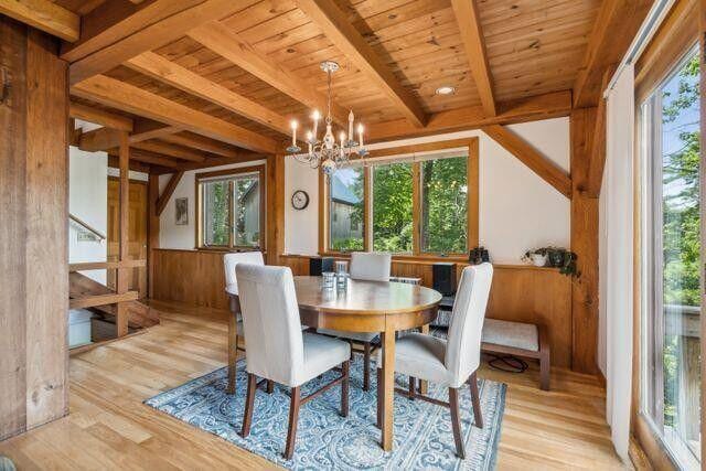 911 Orion Point Way, Harpswell, ME 04079 - dining room featuring a wood ceiling with exposed beams, plenty of natural light, a chandelier, light wood-style floors, and wainscoting