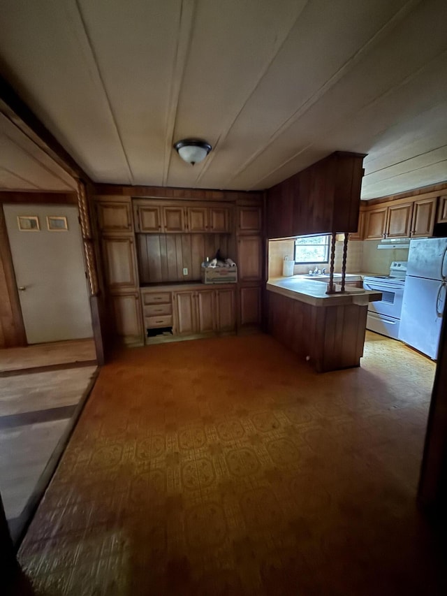 489 Lovejoy Pond Rd, Fayette, ME 04349 - kitchen with a peninsula, refrigerator, white electric range oven, wood walls, and brown cabinetry