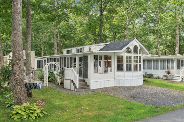191 Tatnic Rd Unit 74, Wells, ME 04090 - view of front facade featuring a sunroom, a front lawn, a shingled roof, and driveway