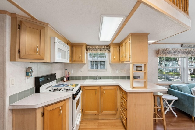 191 Tatnic Rd Unit 74, Wells, ME 04090 - kitchen featuring white appliances, a textured ceiling, a peninsula, light wood-style flooring, and a breakfast bar