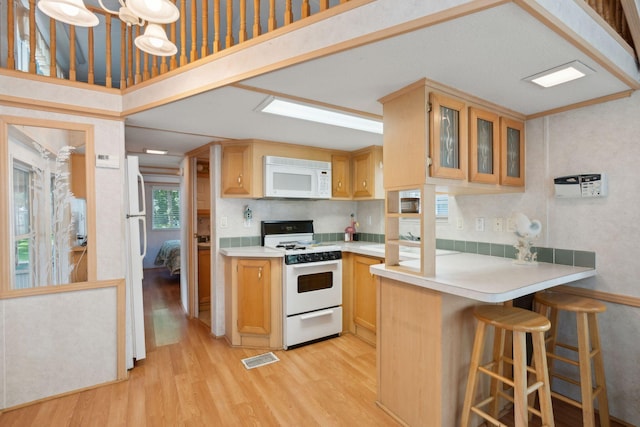 191 Tatnic Rd Unit 74, Wells, ME 04090 - kitchen featuring white appliances, light wood-style floors, light countertops, glass insert cabinets, and a peninsula