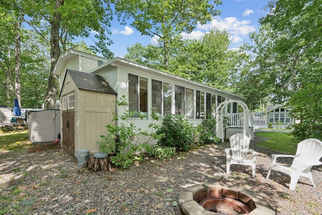 191 Tatnic Rd Unit 74, Wells, ME 04090 - rear view of property featuring a fire pit, a storage shed, and a sunroom