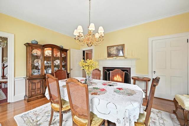 43 Green St, Augusta, ME 04330 - dining room featuring ornamental molding, a chandelier, wood finished floors, and a lit fireplace