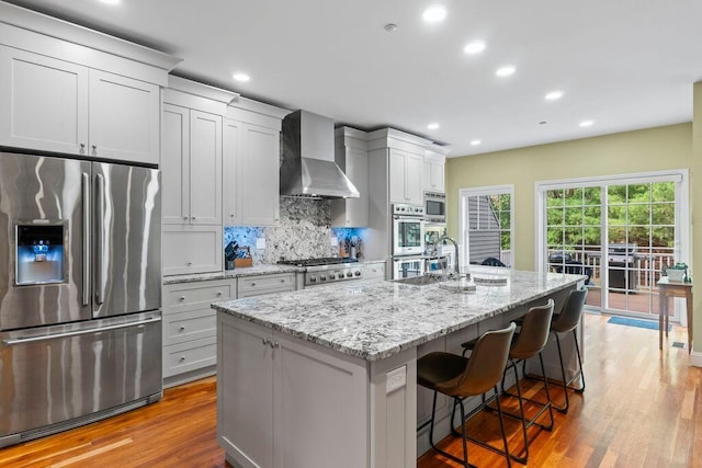 38 Harvest Hill Ln Unit 38, Auburn, ME 04210 - kitchen featuring stainless steel appliances, wall chimney range hood, light wood-style floors, decorative backsplash, and recessed lighting