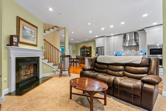 38 Harvest Hill Ln Unit 38, Auburn, ME 04210 - living area with stairs, a glass covered fireplace, recessed lighting, and light colored carpet