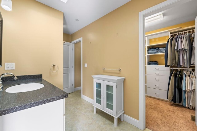 38 Harvest Hill Ln Unit 38, Auburn, ME 04210 - bathroom featuring vanity, a walk in closet, and tile patterned floors