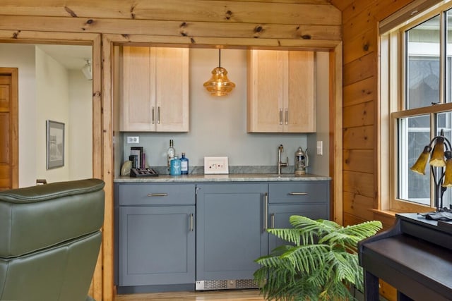 1 Grimes Ave, Boothbay, ME 04544 - kitchen with gray cabinets, wood walls, hanging light fixtures, and light stone counters