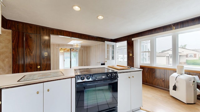 307 Russell St, Lewiston, ME 04240 - kitchen featuring black range with electric cooktop, light wood-style flooring, plenty of natural light, wooden walls, and white cabinetry