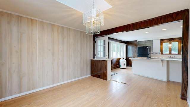 307 Russell St, Lewiston, ME 04240 - kitchen with freestanding refrigerator, light wood-style floors, a chandelier, a peninsula, and decorative light fixtures