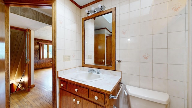 307 Russell St, Lewiston, ME 04240 - half bathroom featuring tile walls, vanity, wood-type flooring, and ornamental molding