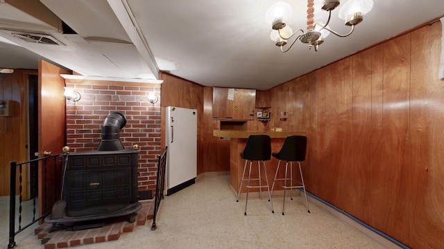 307 Russell St, Lewiston, ME 04240 - kitchen featuring a wood stove, wooden walls, light floors, freestanding refrigerator, and brown cabinets