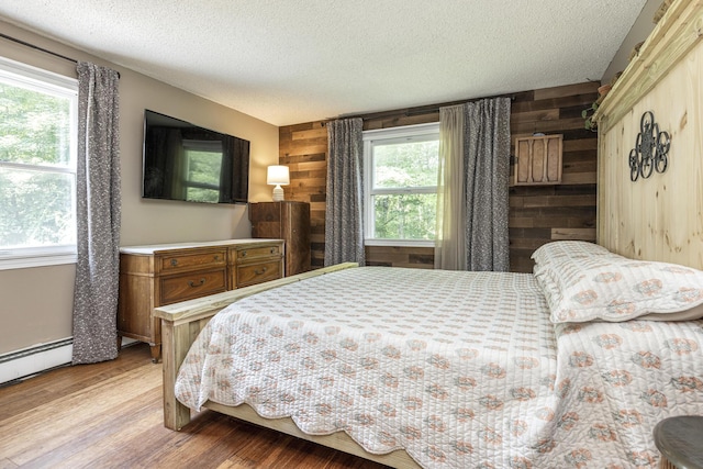 14 Bailey Ln, Brunswick, ME 04011 - bedroom with wooden walls, a textured ceiling, light wood-style flooring, and a baseboard heating unit
