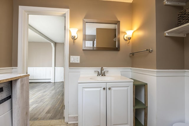 14 Bailey Ln, Brunswick, ME 04011 - bathroom featuring wainscoting, vanity, washer / dryer, a baseboard heating unit, and wood finished floors