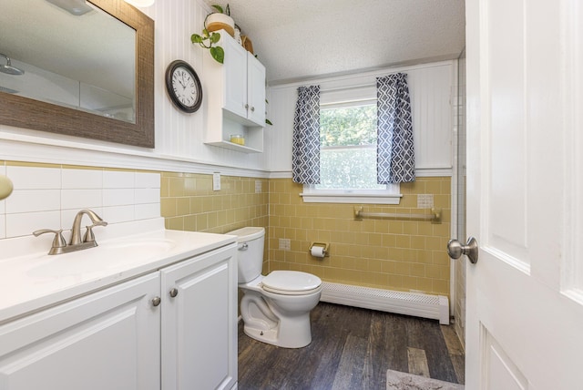 14 Bailey Ln, Brunswick, ME 04011 - bathroom featuring a baseboard radiator, wood finished floors, vanity, a wainscoted wall, and tile walls
