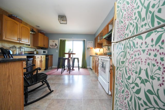 3922 Union St, Levant, ME 04456 - kitchen featuring white appliances, brown cabinets, extractor fan, dark countertops, and light tile patterned floors