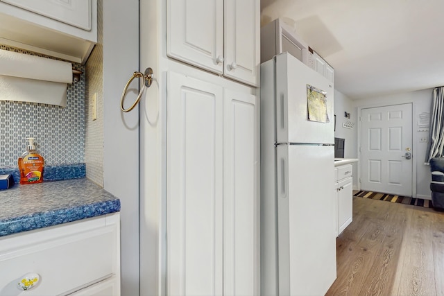 76 Post Rd Unit 17M & 18M, Wells, ME 04090 - kitchen with freestanding refrigerator, light wood-type flooring, white cabinets, tasteful backsplash, and dark countertops