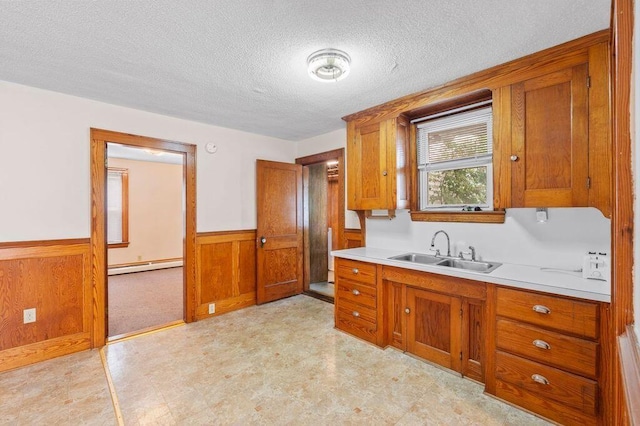 99 Hill St, Biddeford, ME 04005 - kitchen with brown cabinetry, wainscoting, a textured ceiling, light countertops, and light flooring