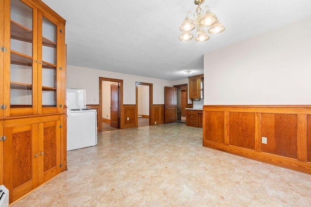 99 Hill St, Biddeford, ME 04005 - unfurnished living room featuring a wainscoted wall, a chandelier, light floors, and a baseboard radiator