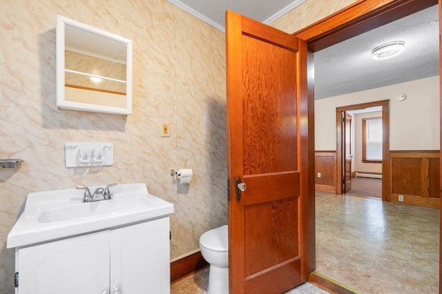 99 Hill St, Biddeford, ME 04005 - half bathroom with vanity, wainscoting, a baseboard radiator, and a textured ceiling