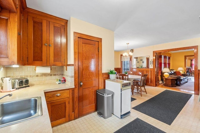 99 Hill St, Biddeford, ME 04005 - kitchen with light countertops, wainscoting, a chandelier, decorative backsplash, and brown cabinets