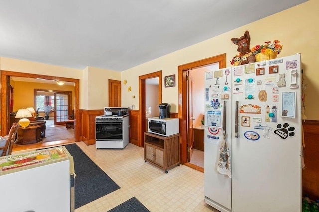99 Hill St, Biddeford, ME 04005 - kitchen with white appliances, a wainscoted wall, light floors, and brown cabinetry