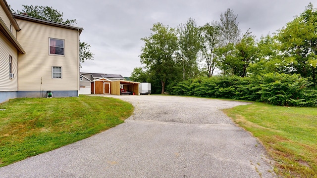 28 Stewart St, Lewiston, ME 04240 - view of side of home with a storage unit, a lawn, and asphalt driveway