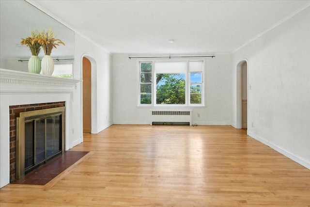 49 Bardwell St, Lewiston, ME 04240 - unfurnished living room featuring crown molding, arched walkways, radiator, a fireplace with flush hearth, and wood finished floors