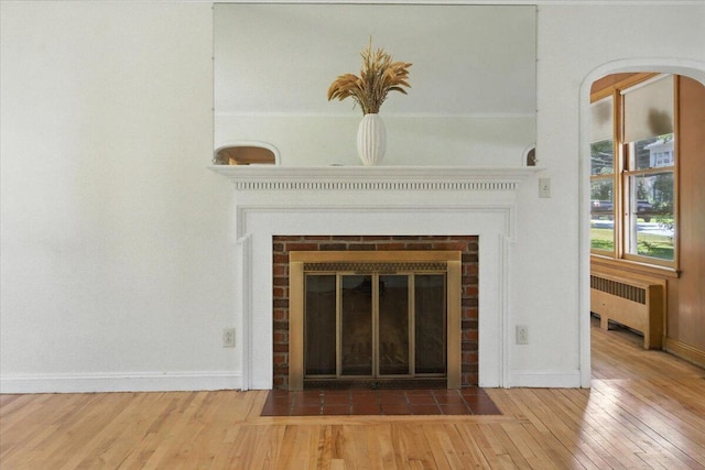 49 Bardwell St, Lewiston, ME 04240 - detailed view of wood finished floors, radiator heating unit, and a brick fireplace