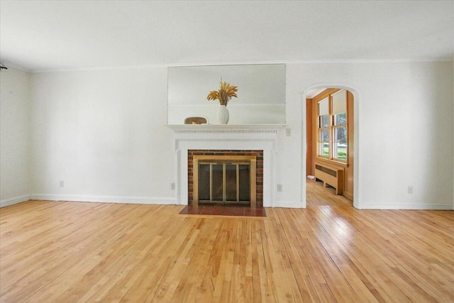 49 Bardwell St, Lewiston, ME 04240 - unfurnished living room featuring crown molding, wood-type flooring, radiator heating unit, a fireplace, and arched walkways